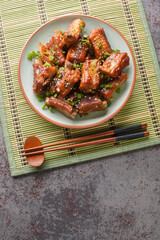 Wall Mural - Fried pork short ribs in sweet and sour sauce in Asian style close-up in a plate on the table. vertical top view from above