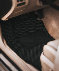 Wall Mural - Driver-side black floor mats made of ethylene vinyl acetate shortened for EVA. Dark floor mats in the light interior of the car.