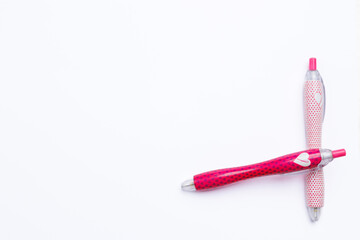 Two pink pens that overlap on a white background. The sign of cancer is drawn on the pen, the campaign against cancer.