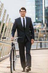 Wall Mural - Young handsome man with business suit driving bicicyle to go to office - Corporate businessman portrait biking in the city, concepts about business, green mobility and lifestyle