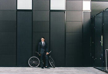 Wall Mural - Young handsome man with business suit driving bicicyle to go to office - Corporate businessman portrait biking in the city, concepts about business, green mobility and lifestyle