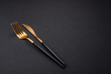 Wall Mural - Metal kitchen knife and fork on a dark textured concrete background