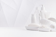 Cosmetic Products For Body Care, Cleansing Skin In White Bottles With Toiletry - Towels, Bath Salt, Sponge In Elegant Soft Light White Bathroom Interior In Geometric Futuristic Style, Copy Space.