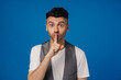 © Drobot Dean - Young white man holding finger at mouth while gesturing silence sign