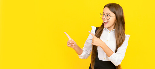 Canvas Print - happy teen girl in glasses for vision protection pointing finger on copy space. Child face, horizontal poster, teenager girl isolated portrait, banner with copy space.