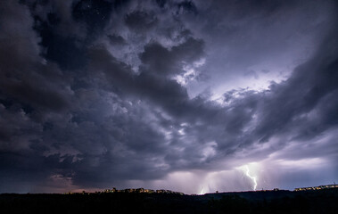 Beautiful thunderstorm with clouds and lightning over the night city