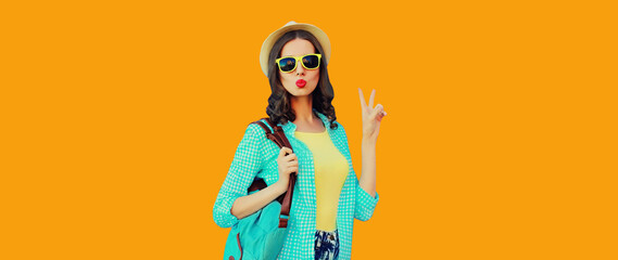 Portrait of beautiful young woman posing wearing summer straw hat, backpack on orange background