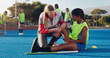 © Kobus L/peopleimages.com - Woman, sports and knee injury in hockey training, practice or game on a blue turf with coach and team. Sport mentor helping female in leg pain, accident or bruise from physical activity during match