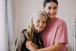 © 1st footage - Happy caregiver and senior patient smiling and looking at camera, Senior woman and doctor at home health care visit, Home care and nursing concept