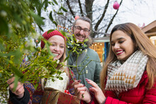 Friends Holding Gifts And Mistletoe Twigs
