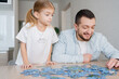 © Julija - father and daughter playing with puzzles at home. Focus on man.