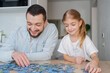 © Julija - father and daughter playing with puzzles at home. Focus on man.