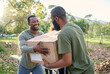 © N Felix/peopleimages.com - Black man, charity and holding box in park of donation, community service or social responsibility. Happy guy, NGO workers and team helping with package for volunteering, support and society outreach