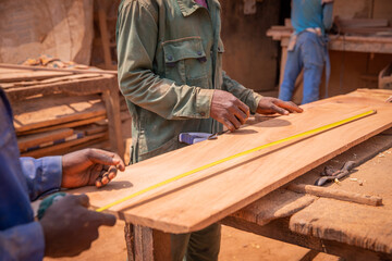 close-up of carpenters' hands taking measurements of a wooden plank, carpentry work.