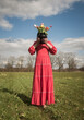 © Milou Dirks - woman in long classic red dress standing in field in early spring holding vase with colorful tulips