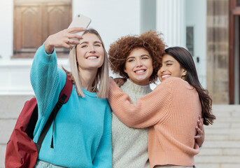 Wall Mural - Women students, selfie and smile with hug at college campus for goals, diversity and social network. Gen z woman, group and smartphone with embrace, happiness and studying at university for success