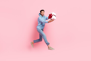 Wall Mural - Full length photo of overjoyed nice man wear stylish blue clothes moving empty space carrying you gift isolated on pink color background