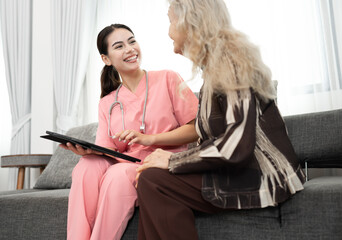 Wall Mural - Beautiful nurse take care older caucasian woman of use tablet computer at home