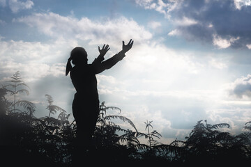 Christ religion and christianity worship or pray concept.Silhouette of Christian catholic woman are praying to god in dark sky. Prayer person hand in nature background. Girl believe and faith in jesus