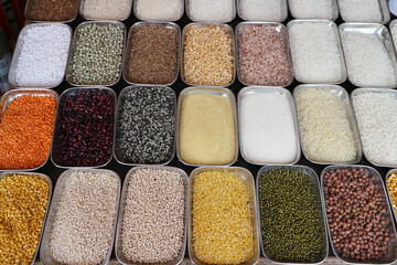 A set of various types of cereals and peas in metal rectangular containers.