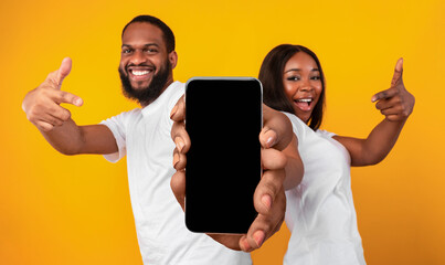 Poster - Black couple pointing at big blank smartphone screen for mockup