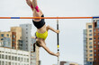 close-up female athlete pole vault on background of buildings