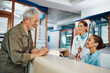 © Drazen - Happy senior man talks to nurse while checking in at doctor's office.