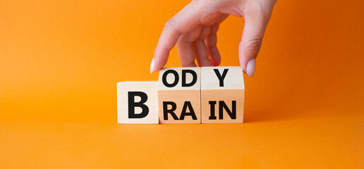 Body vs Brain symbol. Businessman hand turns wooden cubes and changes word Brain to Body. Beautiful orange background. Business and Body vs Brain concept. Copy space.