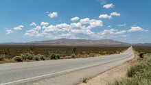 Desert Road Leading To Tehachapi Mountains In The Mojave Region With Passing Clouds And Some Traffic. .
