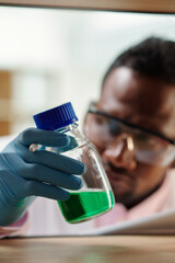 Wall Mural - Scientist taking bottle with green reagent for his research