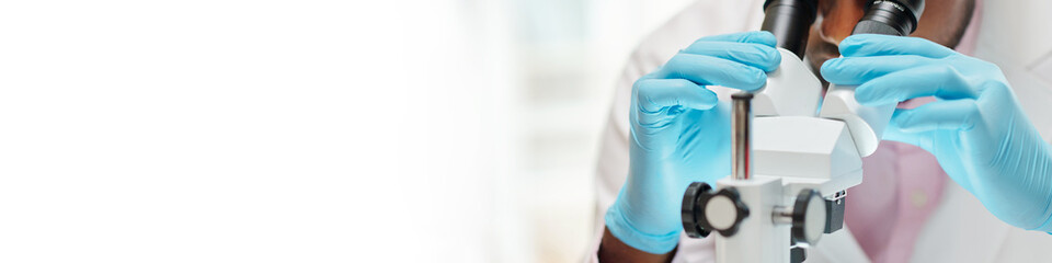 banner with laboratory worker looking at sample through microscope