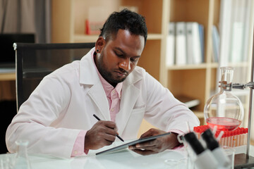 Wall Mural - Serious research center worker filling document on tablet computer