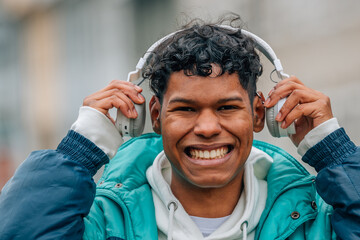 young man with headphones smiling in the street outdoors