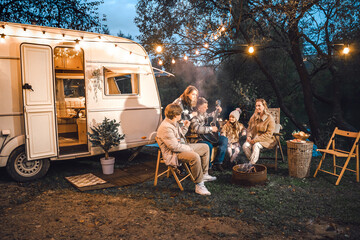 Wall Mural - Family trailer travel.Children,brother sister,mom dad playing guitar,singing song at fire.Evening picnic in nature.Holiday barbecue BBQ food.Vacation weekend dinner.Road lunch.Camper,house on wheels