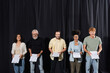 multicultural actors with bearded screenwriter holding clipboards and grimacing at camera during acting skills lesson.