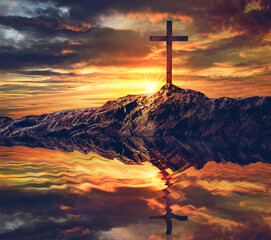 Water reflection of cross silhouette at sunset sky background.