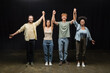 © LIGHTFIELD STUDIOS - full length of young and joyful interracial actors holding raised hands and smiling at camera in theater.