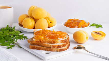 Wall Mural - Toasts of bread with apricot jam and fresh fruits with mint on white wooden table. Tasty breakfast