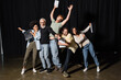 © LIGHTFIELD STUDIOS - full length of excited interracial actors with bearded art director posing with clipboards on stage of theater.