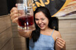 young latina raising the jug of alcohol for a toast while winking at her