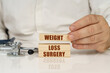 © Dzmitry - On a white surface, a stethoscope and wooden plates with the inscription - Weight Loss Surgery