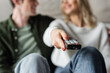 © LIGHTFIELD STUDIOS - cropped view of woman clicking channels with remote controller near boyfriend on blurred background.