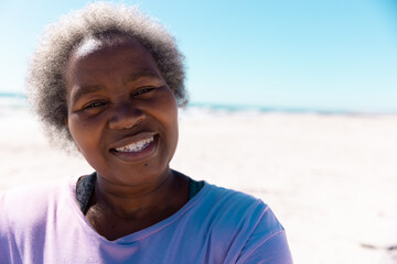 Close-up portrait of african american senior woman with short gray hair smiling at sandy beach