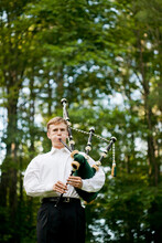 Bagpipe Player In Front Of Trees.