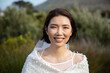 © Wavebreak Media - Portrait of happy asian bride in white dress smiling at outdoor wedding, copy space