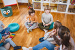 © lordn - Kindergarten teacher with children sitting on the floor having music class, using various instruments and percussion. Early music education