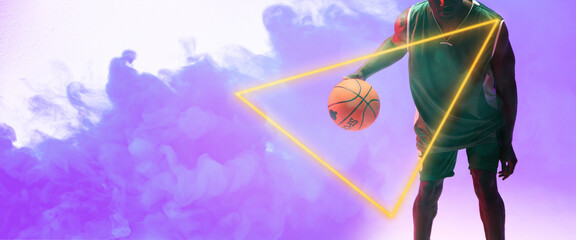 Poster - Midsection of african american male player with basketball by glowing triangle on smoky background