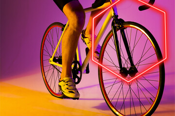 Wall Mural - Illuminated hexagon over low section of caucasian male athlete riding bike on purple background