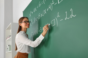 Wall Mural - Young math’s teacher writing mathematical equations near chalkboard in classroom