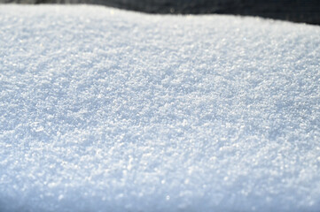 Snow surface on sunny winter day. Close up of fresh white snow texture.